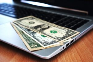 Close-up of US dollar bills placed on a laptop symbolizing digital finance and economy.