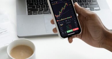 Person analyzing stock market trends on smartphone with laptop background