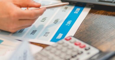 Close-up of a hand using a ballpen and calculator to analyze interest rates on a chart.