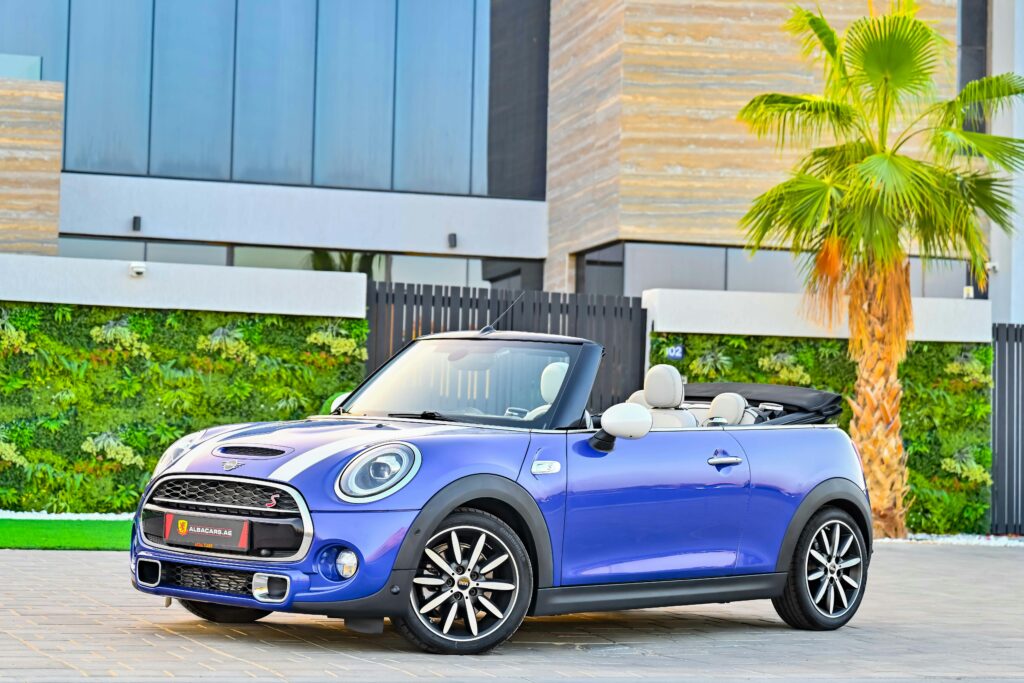 Stylish blue Mini Cooper convertible car parked in sunny Dubai neighborhood.