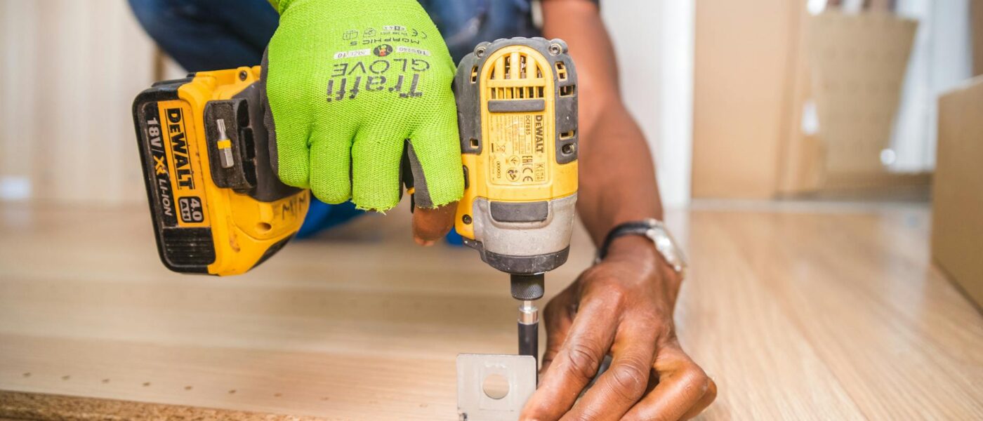 Man using a power drill for home improvement on a wooden floor with precision.