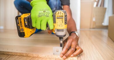 Man using a power drill for home improvement on a wooden floor with precision.