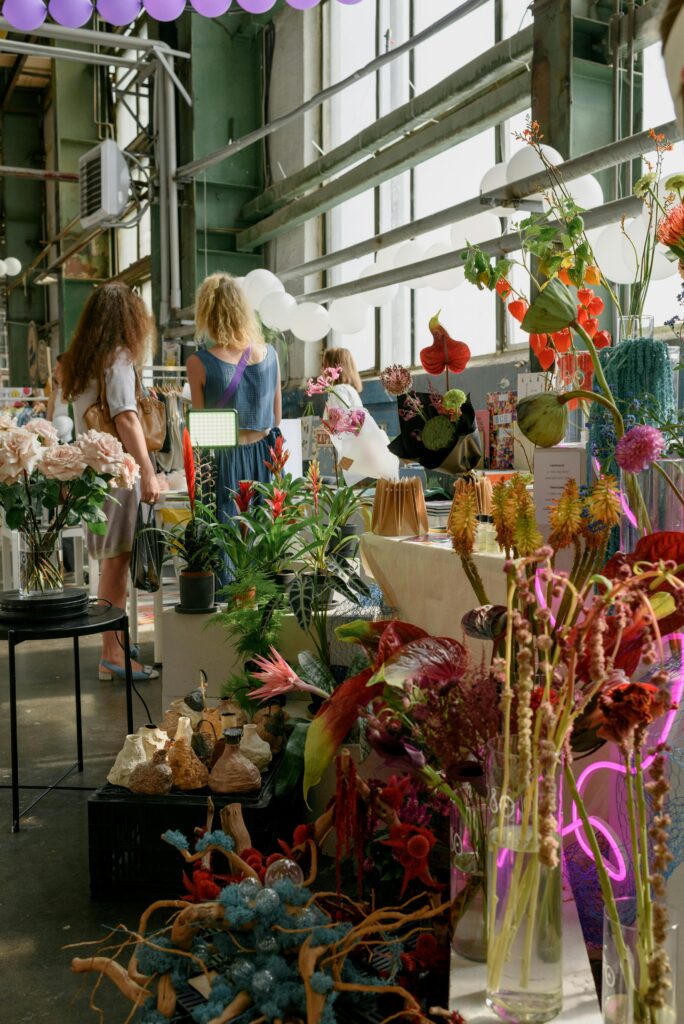 Vibrant flower market scene with decorations and people indoors.