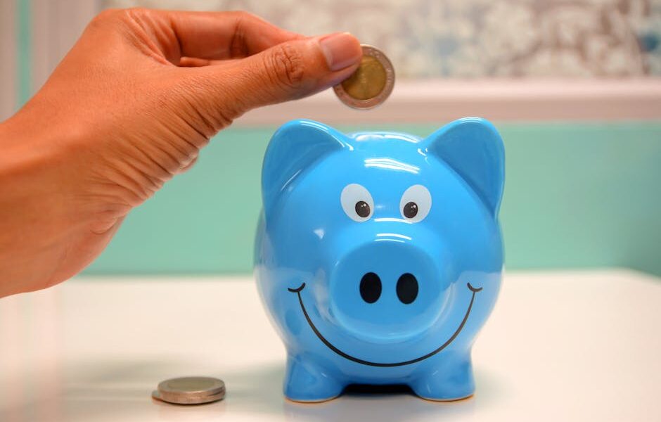 Hand inserting a coin into a blue piggy bank for savings and money management.