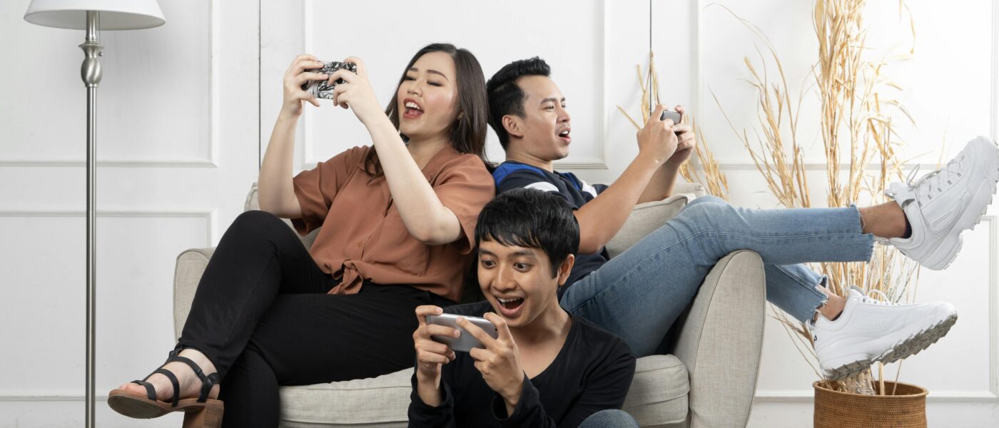 Three friends enthusiastically playing video games indoors, having fun and relaxing.