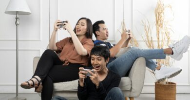 Three friends enthusiastically playing video games indoors, having fun and relaxing.