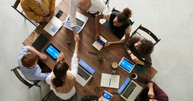 Top view of a diverse team collaborating in an office setting with laptops and tablets, promoting cooperation.