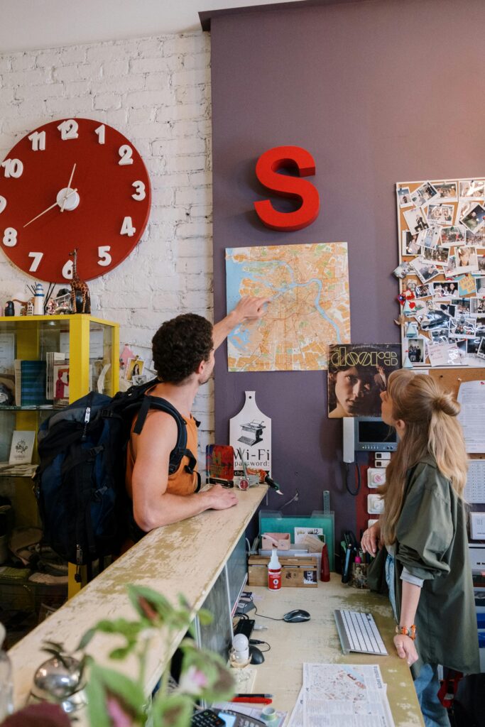 Backpackers consulting map at hostel reception desk for directions.