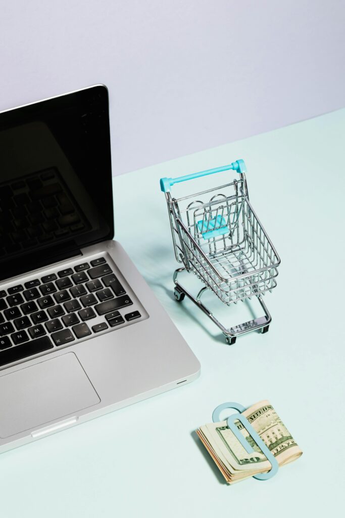 Laptop and mini shopping cart with cash representing online shopping and e-commerce.