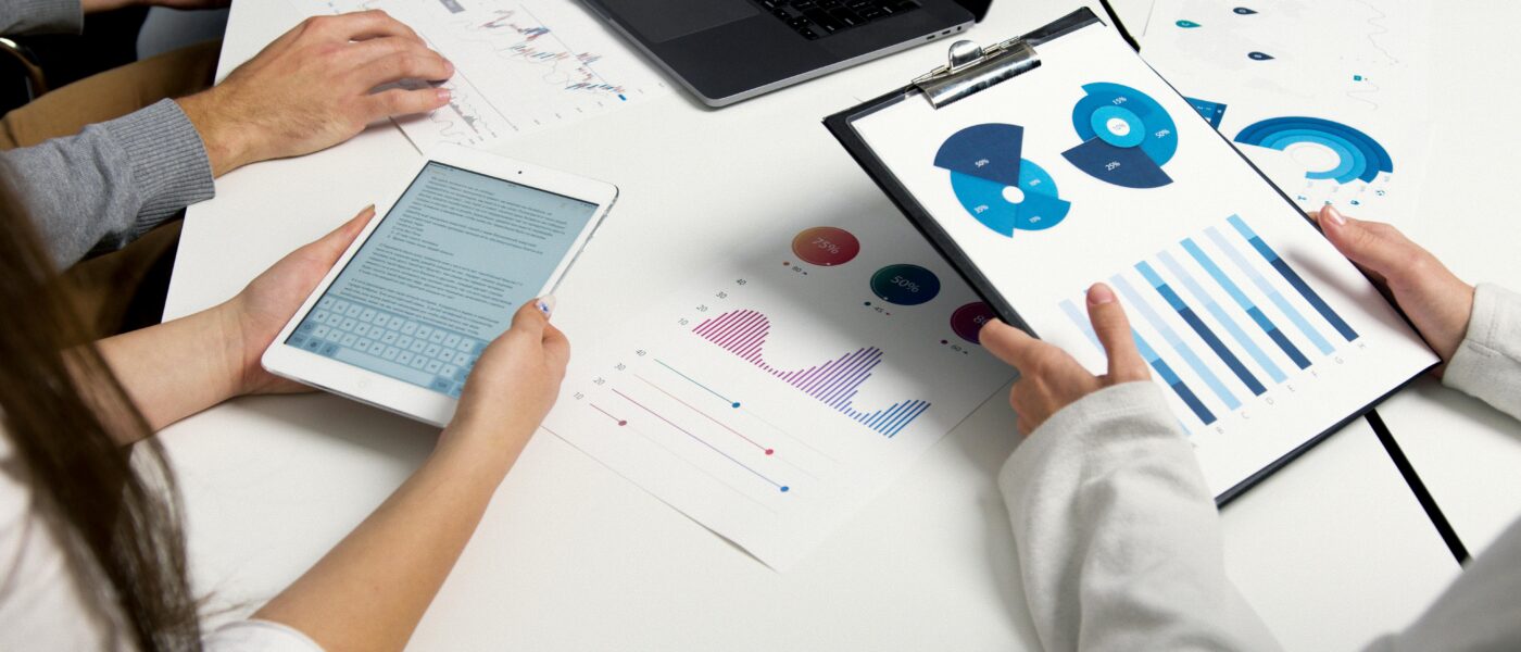 Team analyzing financial charts and digital reports during a business meeting.