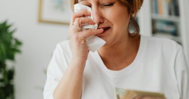 A woman with short hair cries while holding money indoors, showing financial stress.