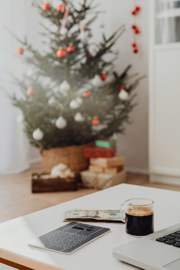 A warm, festive setting with a decorated Christmas tree, presents, and a coffee on a table.