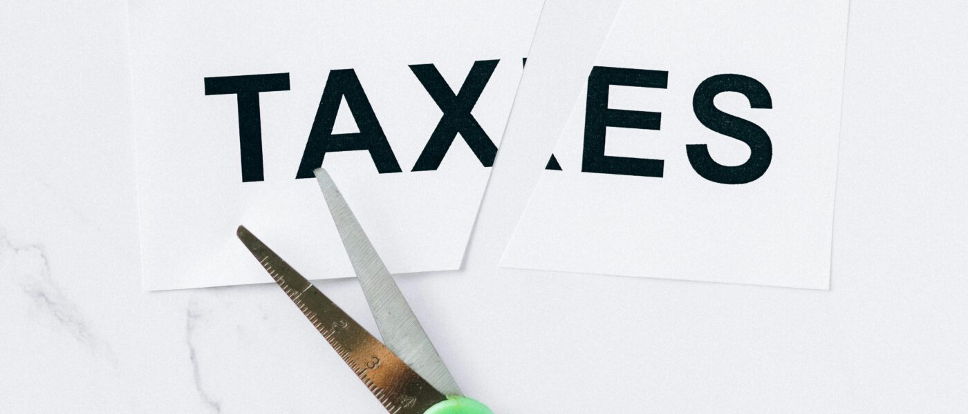 Close-up of scissors cutting the word taxes on a marble background, symbolizing tax reduction.