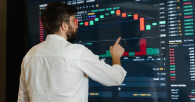 A man analyzes cryptocurrency graphs on a touchscreen monitor in a modern office setting.