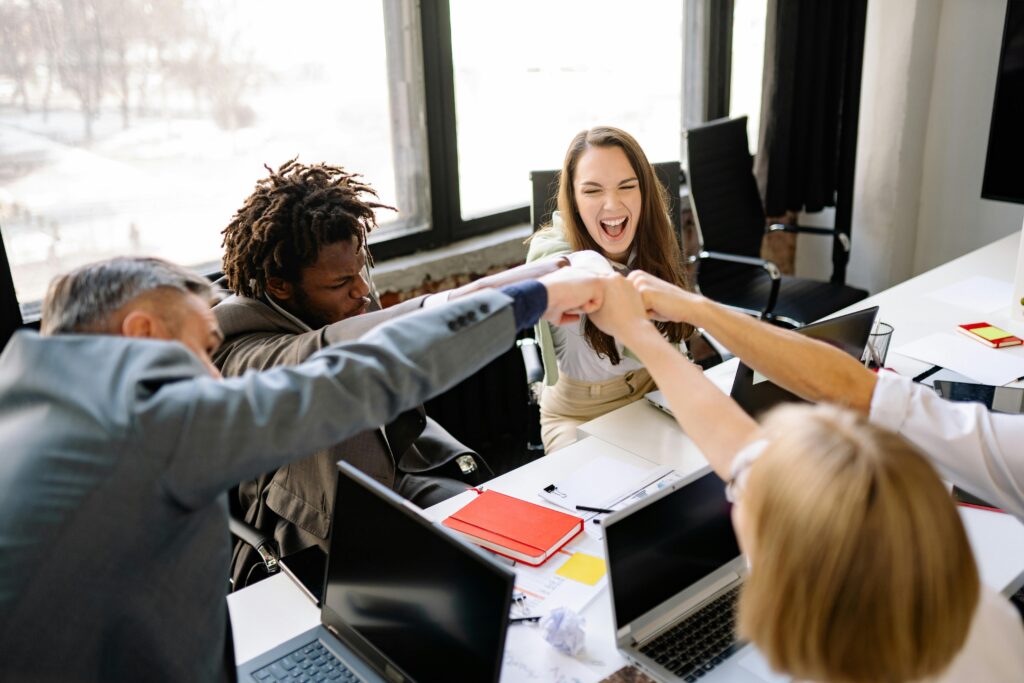 A diverse group of professionals celebrate a successful meeting with a fist bump.