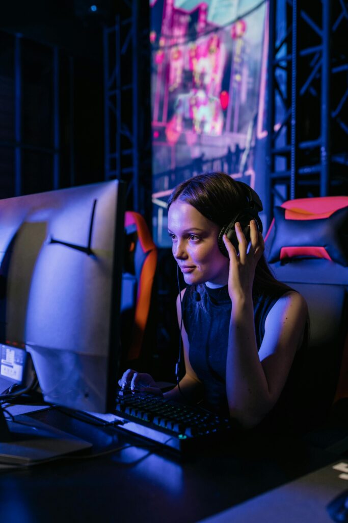 A woman gamer with a headset deeply focused on playing video games in an esports arena.