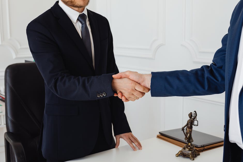 Two men in suits shaking hands in a formal office environment symbolizing an agreement.