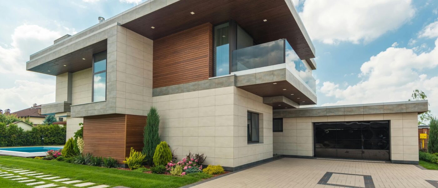 Contemporary luxury house with a sleek design, lush garden, and blue sky.