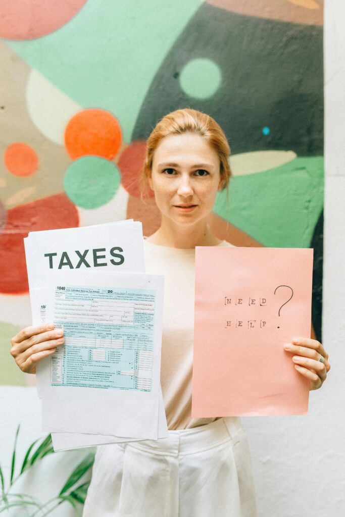 A professional woman holding tax documents and a 'Need Help?' sign, offering tax assistance.