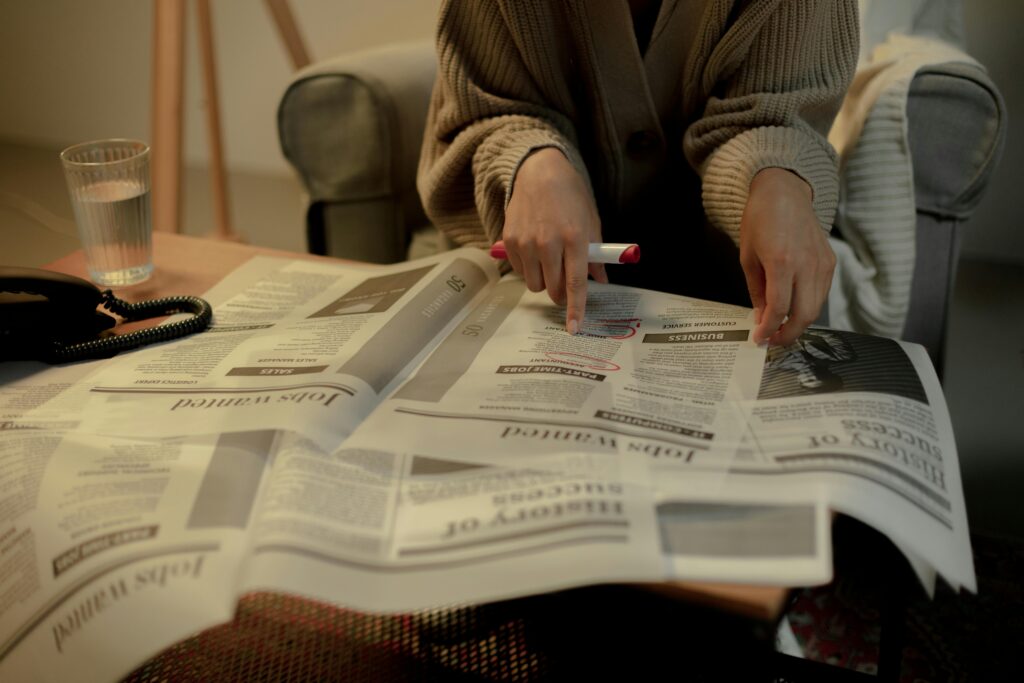 Close-up of a woman reading job listings in a newspaper, highlighting employment search.