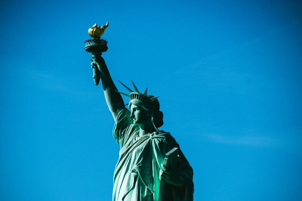 Iconic view of the Statue of Liberty with a bright blue sky, symbolizing freedom in New York.