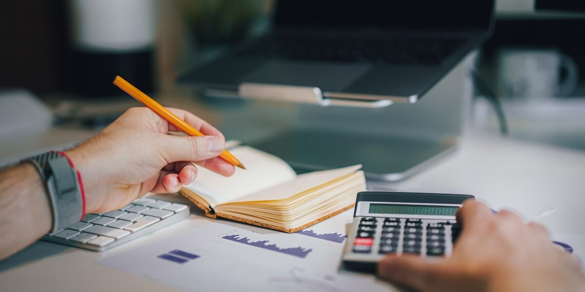 Person calculating a budget for irregular income with a calculator and notebook