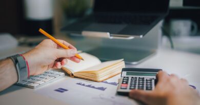 Person calculating a budget for irregular income with a calculator and notebook