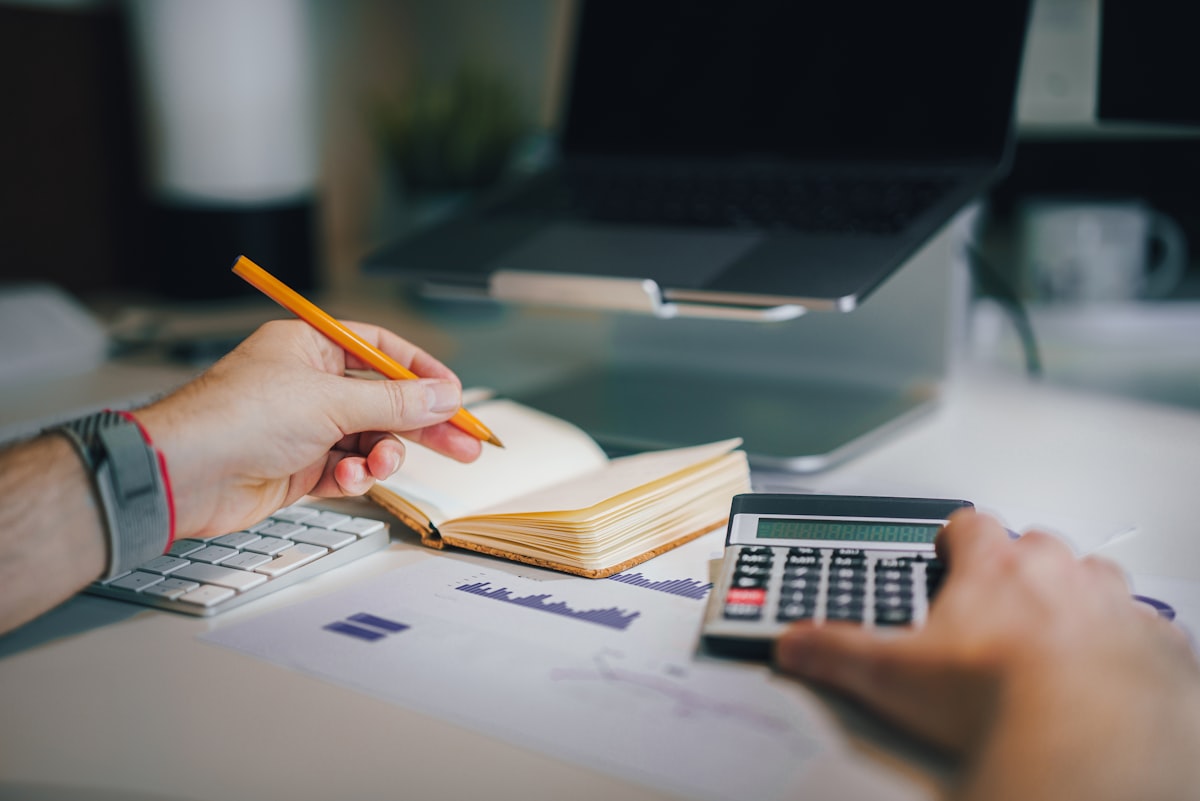 Person calculating a budget for irregular income with a calculator and notebook