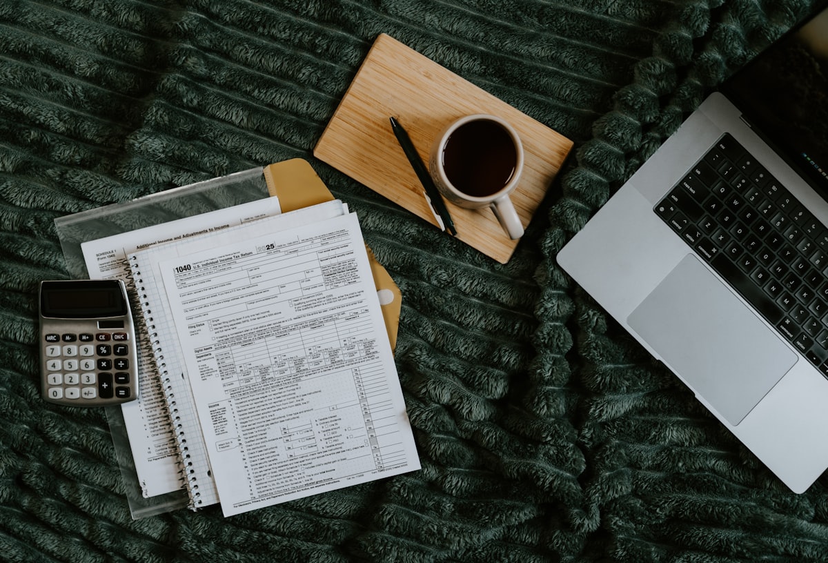 Tax forms, calculator, and laptop for tracking irregular income month to month