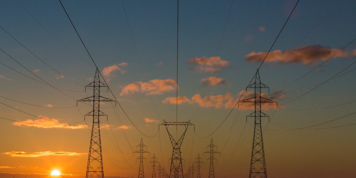 Power transmission towers at sunset, the grid that AI energy infrastructure stocks are built to expand