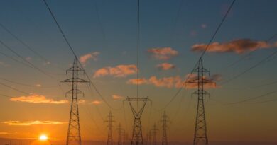Power transmission towers at sunset, the grid that AI energy infrastructure stocks are built to expand
