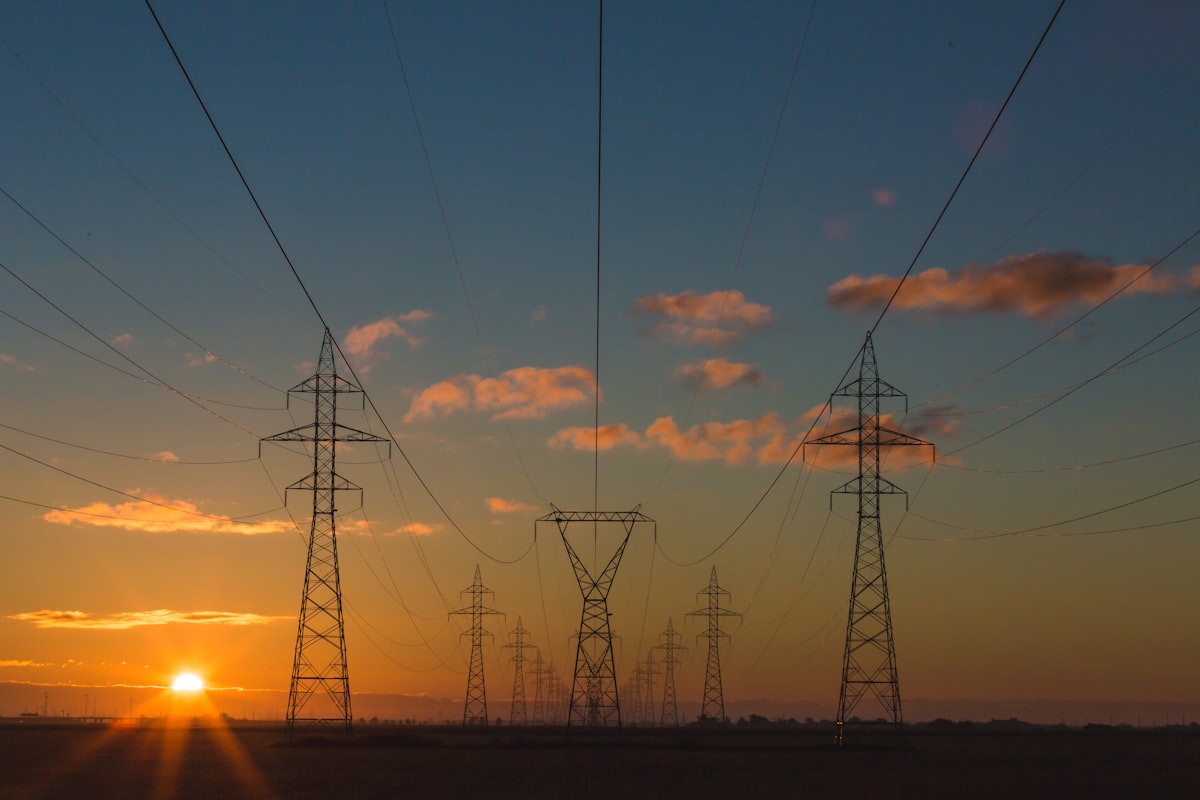 Power transmission towers at sunset, the grid that AI energy infrastructure stocks are built to expand