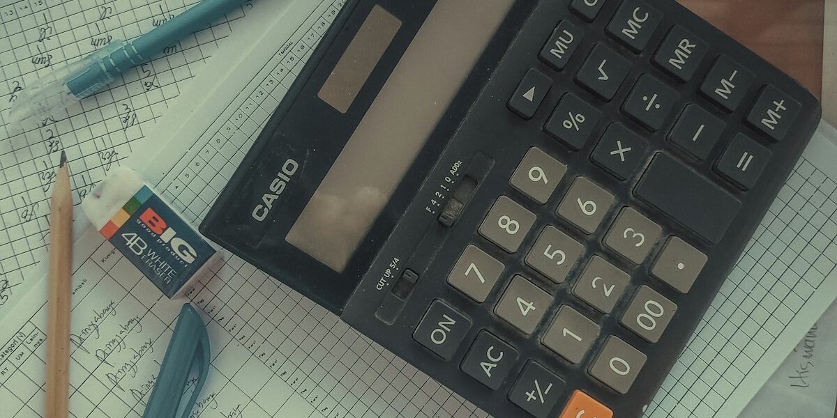 A calculator on a stack of papers representing the debt settlement vs debt payoff decision