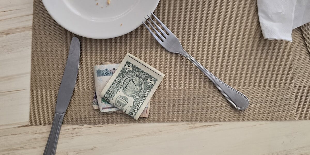A couple reviewing bills and cash on the table while working out how to pay off debt on a low income
