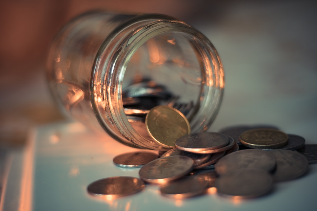 A jar of saved coins showing the slow steady progress you make when you pay off debt on a low income