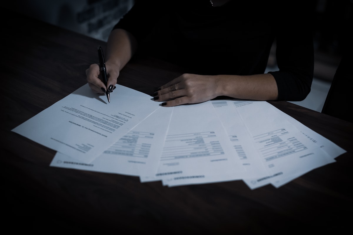 A person signing a contract representing the risks of a debt settlement agreement