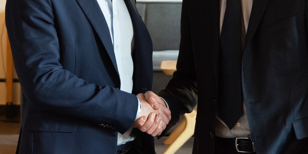 Two business partners shaking hands, representing how to become a millionaire in 2026 by acquiring a business
