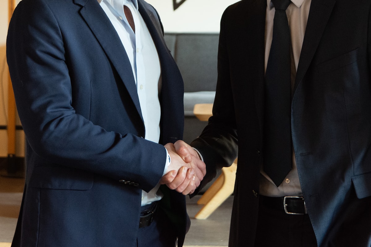 Two business partners shaking hands, representing how to become a millionaire in 2026 by acquiring a business