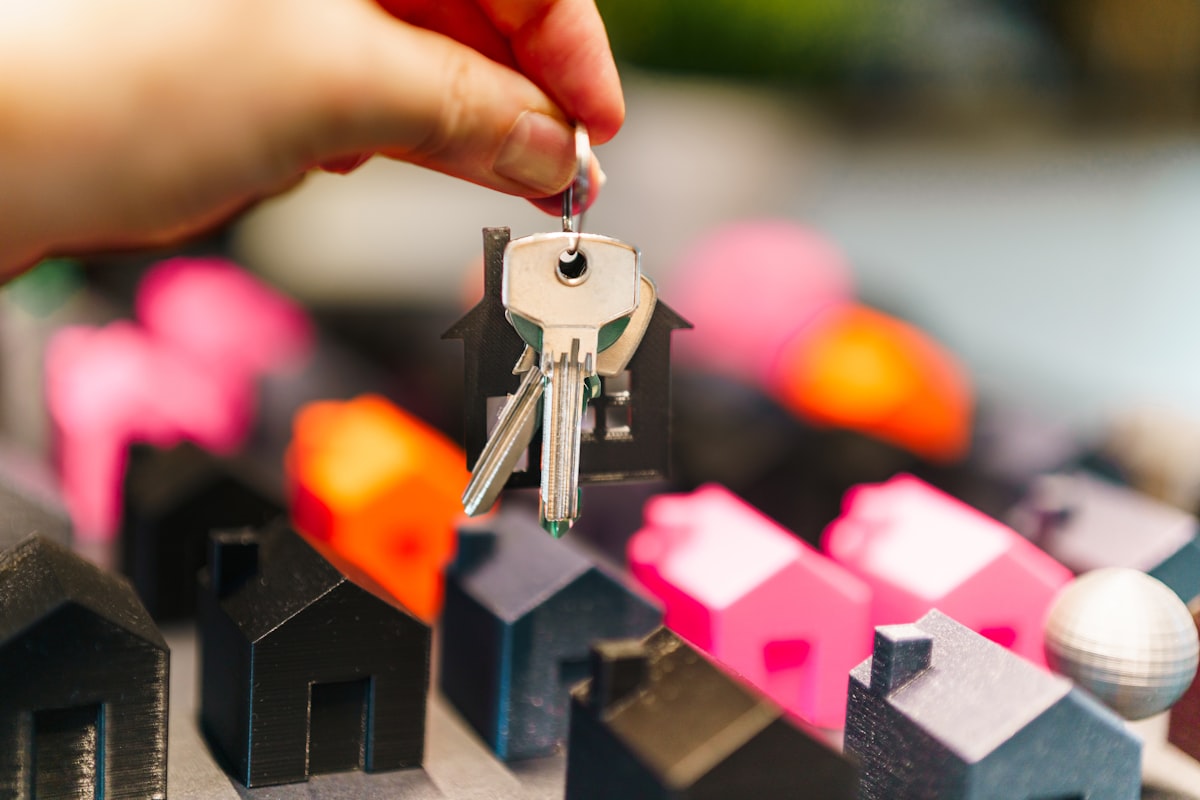Hand holding house keys over miniature homes, representing using a line of credit to buy real estate