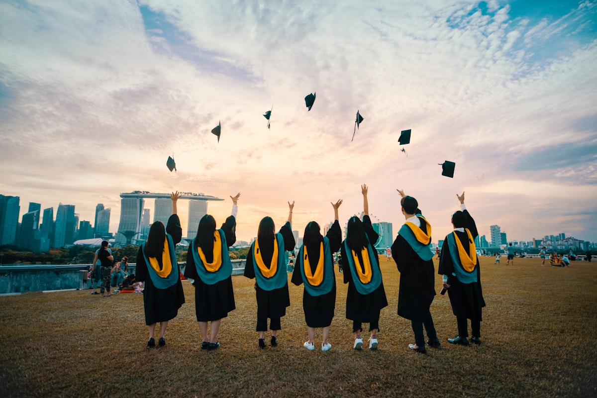 Graduates celebrating after paying for college, before they pay off student loans fast