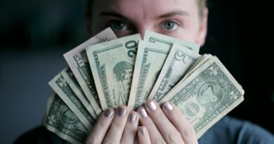 Person holding fanned-out dollar bills, representing how much to invest each month